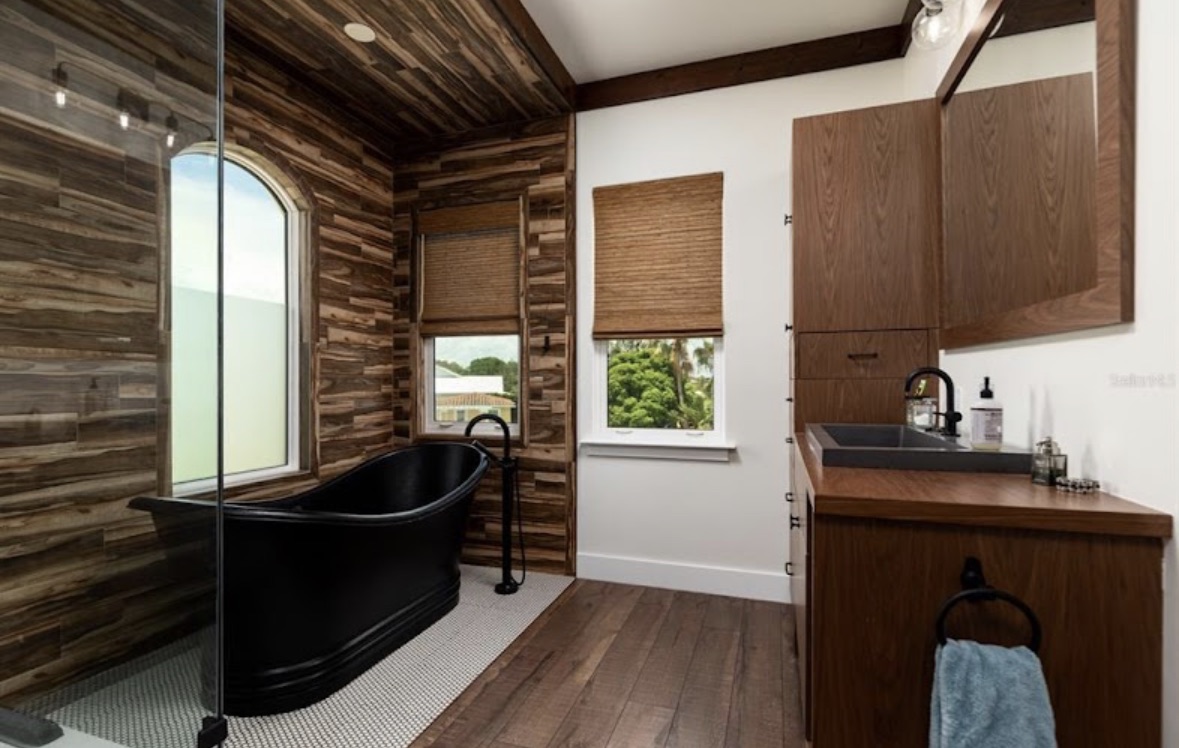 Bathroom with a freestanding black tub and reclaimed wood walls