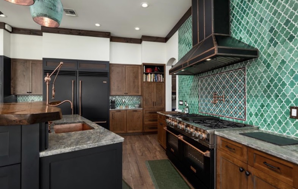 Custom kitchen with handmade green tile, copper fixtures, and warm wood cabinetry
