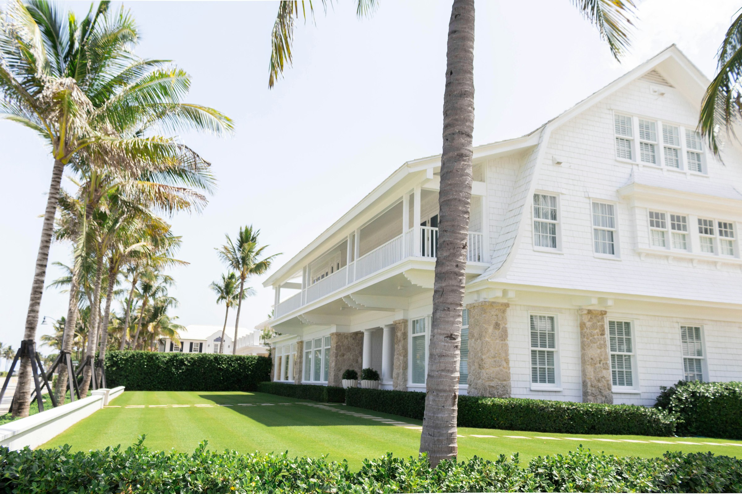 White coastal home with palm trees and a manicured lawn